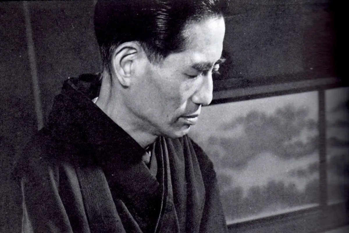 A black-and-white portrait of the composer Michio Miyagi in a kimono, eyes lowered, seated at his koto